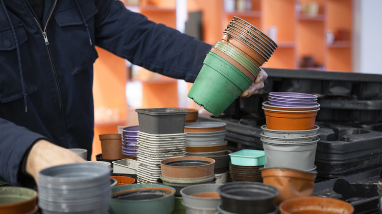 A person holds up a stack of plastic nursery pots in assorted colors to examine them.