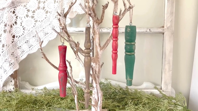 Chair spindles painted in different colors with strings attached hanging on a tree