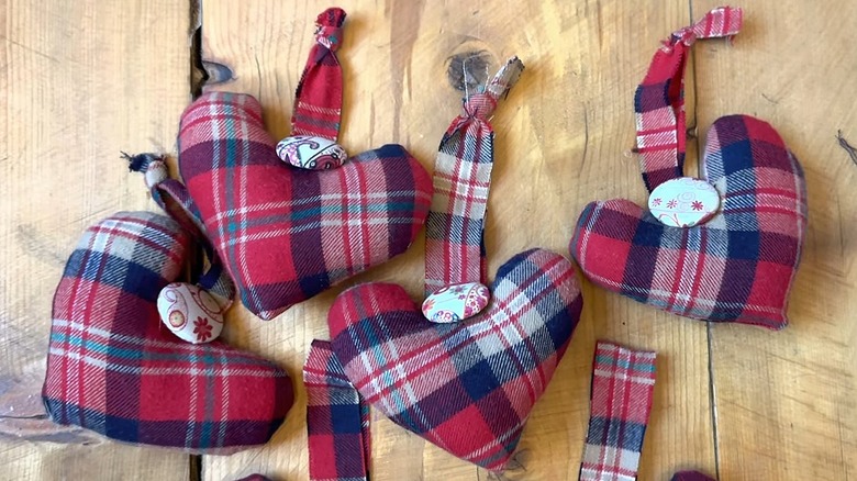 Red flannel heart ornaments laying on a wood table