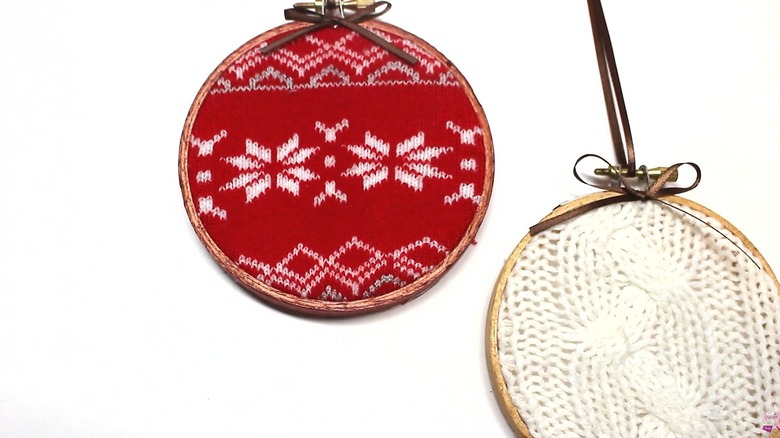 Two sweater ornaments laying on a white table