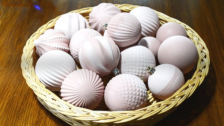 Basket full of old ornaments that have been painted in neutral tones