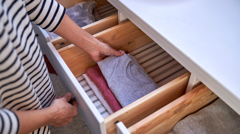 A woman reaching into a lined drawer