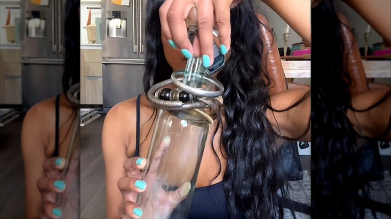 woman putting bracelets on emptying wine bottle neck for storage