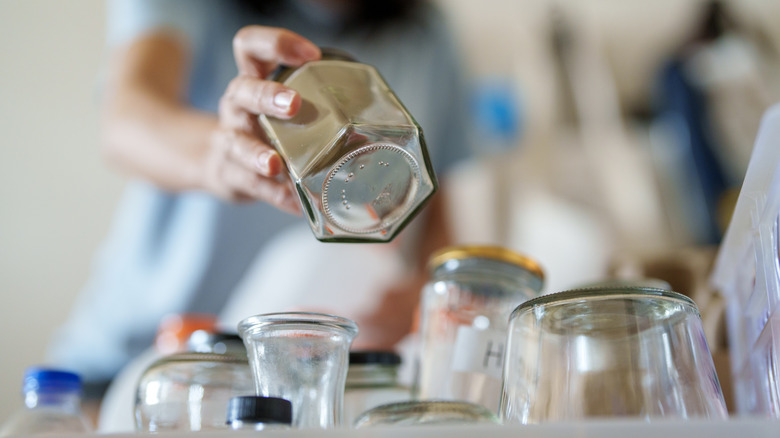 A person sorts a selection of empty jars.