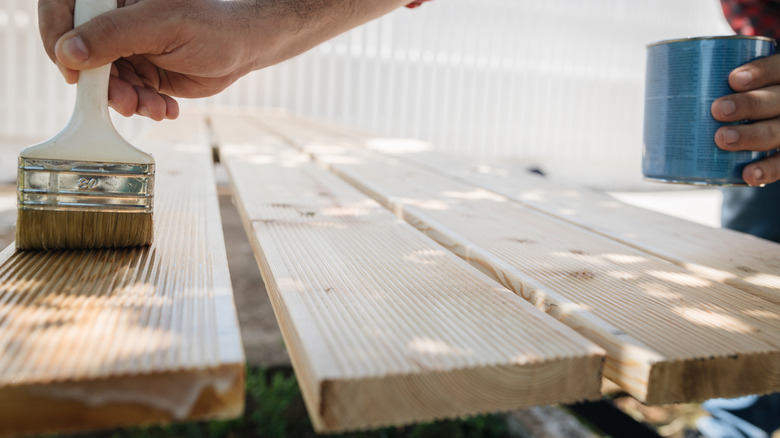 Person staining wood planks