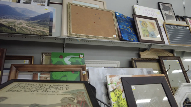 Two shelves of thrifted picture frames.