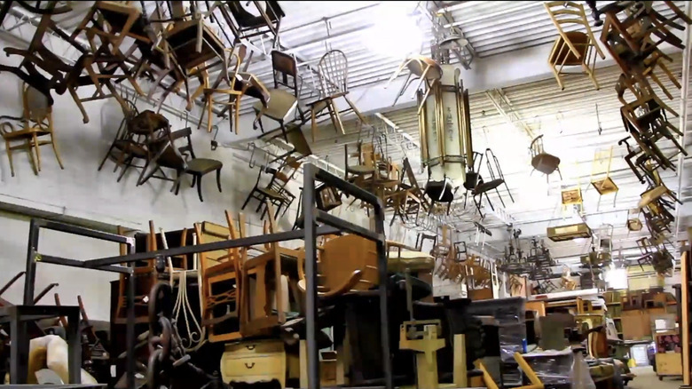 A large warehouse with vintage chairs hanging from the ceiling.