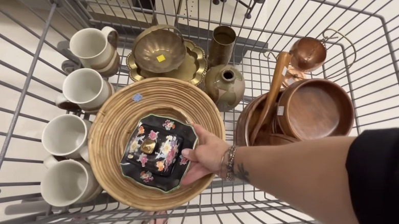 A hand placing a vintage butter dish in a cart with dishes.