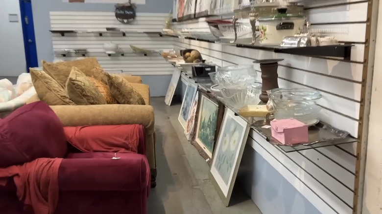 A thrift store with two sofas and shelves of home goods.