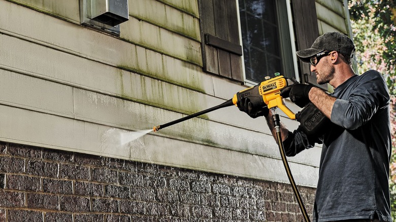 A man pressure washing a house