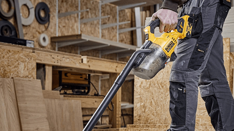 A man using DeWalt's handheld vacuum.