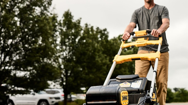 A man pushing a DeWalt electric lawn mower.