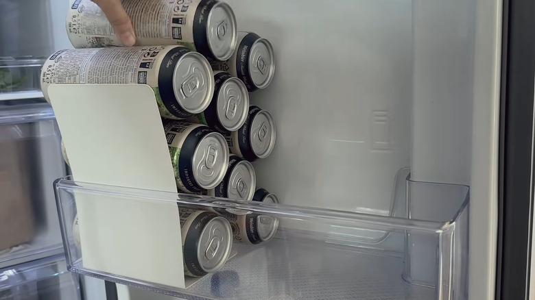 stack cans in a fridge door with the help of a metal bookend