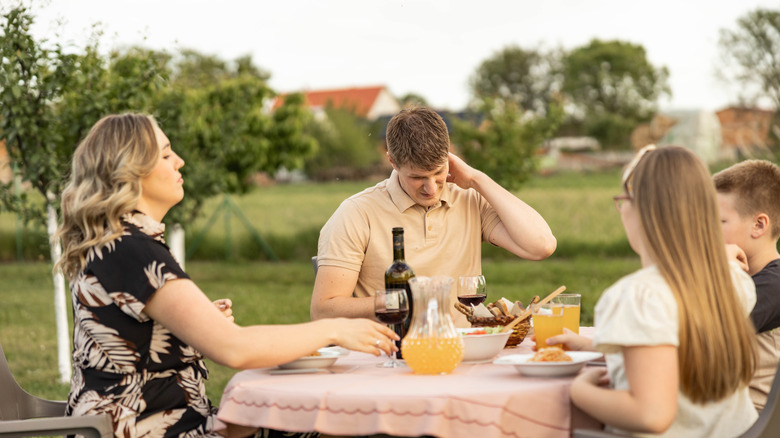 Man sitting outside scratching neck from mosquito bite