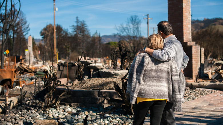 a man and woman looking at their home after a natural disaster
