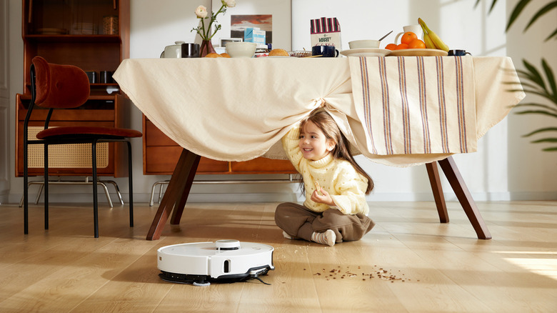 White robot vacuum beside girl