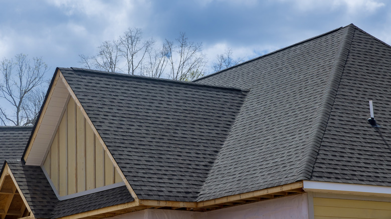Dark gray asphalt shingle roof on large house in construction