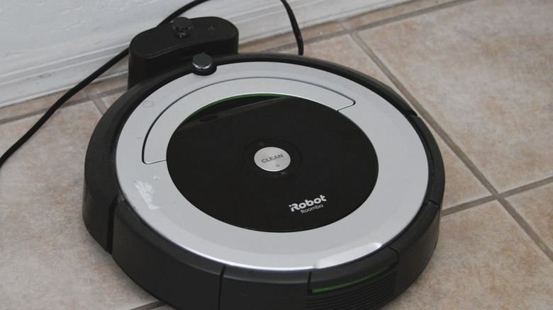 A black Roomba docked in the charging station