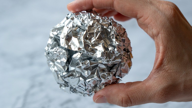 Hand holding aluminum foil ball