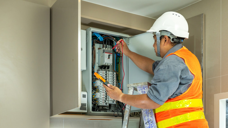 Electrician inspecting a panel behind cabinet doors