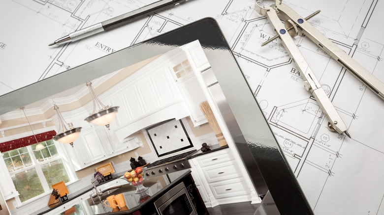 Kitchen design on tablet lying on blueprints 