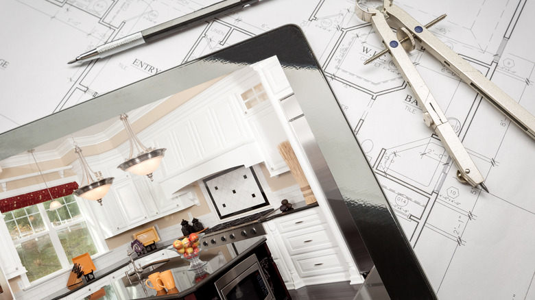 Kitchen design on tablet lying on blueprints