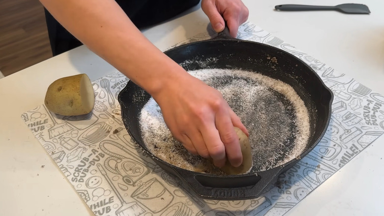 Removing rust from a pan by scrubbing with potato and salt