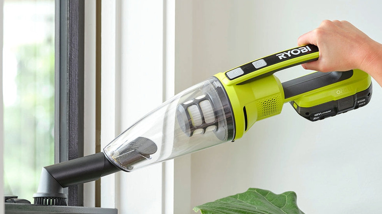 Someone using the brush tool to grab dust with hand vacuum