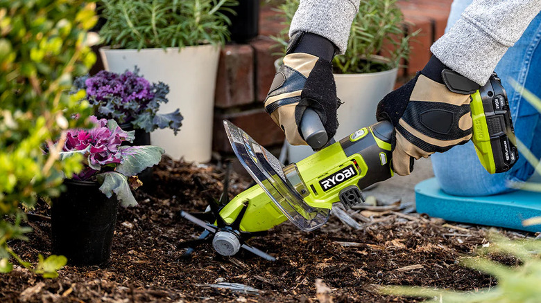 Close-up of a gardener preparing flower bed soil with Ryobi's 18V One+ Cordless Compact Battery Cultivator