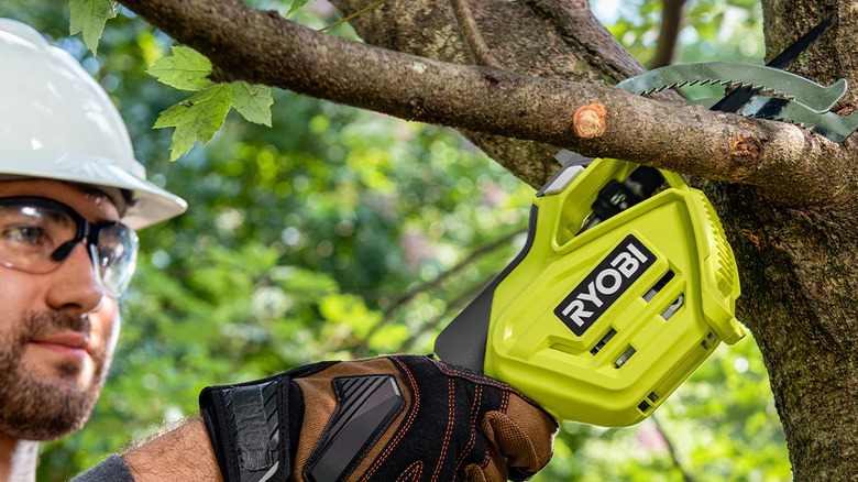 A man sawing a tree branch away with Ryobi's 18V One+ Electric Cordless Pruning Reciprocating Saw