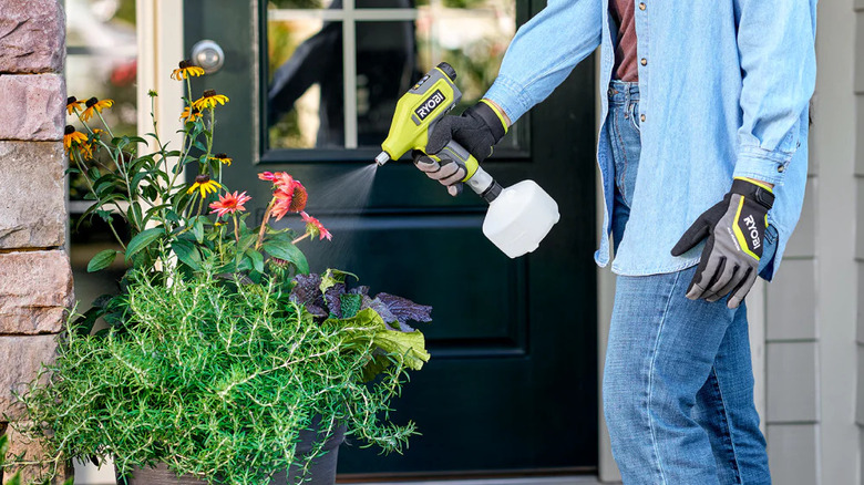 A gardener dousing potted flowers with Ryobi's USB Lithium Cordless Compact Sprayer