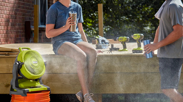 A couple talking as Ryobi's 18V One+ 7 ½-inch Bucket Misting Fan keeps them cool