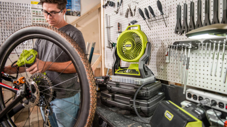 A person working with a Ryobi power tool, with a Ryobi fan in the background