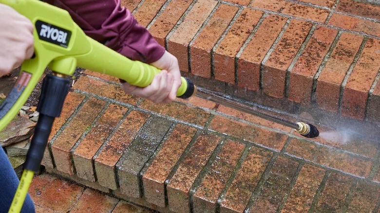 Person pressure washing brick steps