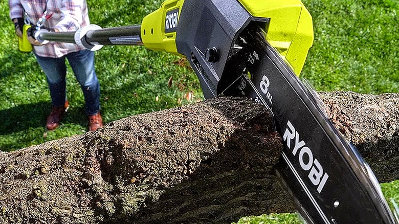The Ryobi 18V One+ 8-Inch Pole Saw being used to cut a large branch from a tree