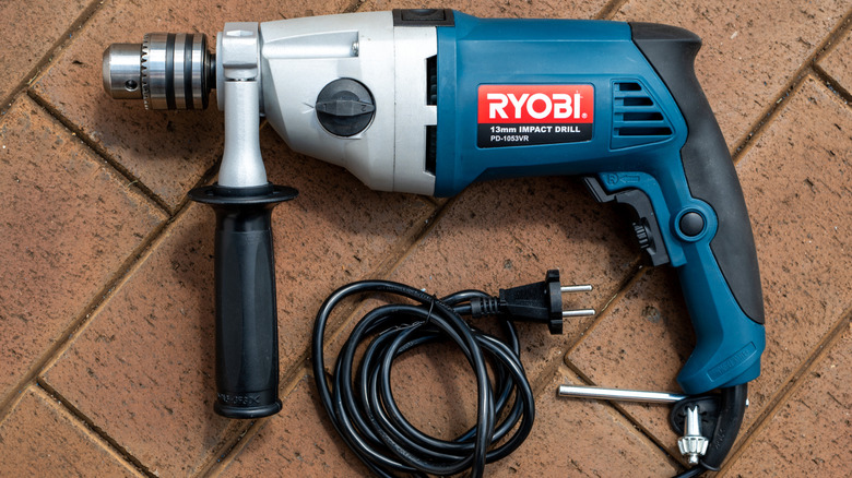 A blue Ryobi impact drill on a brick surface