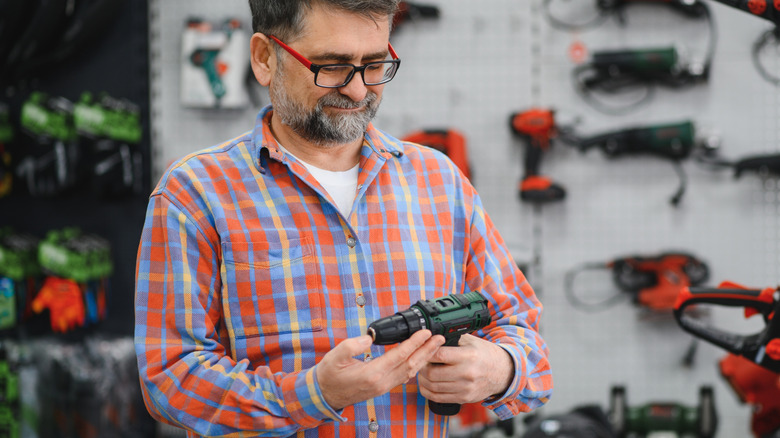 A man in a hardware store choosing a cordless drill driver