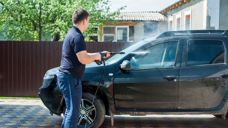 A man cleaning a car with a portable pressure washer