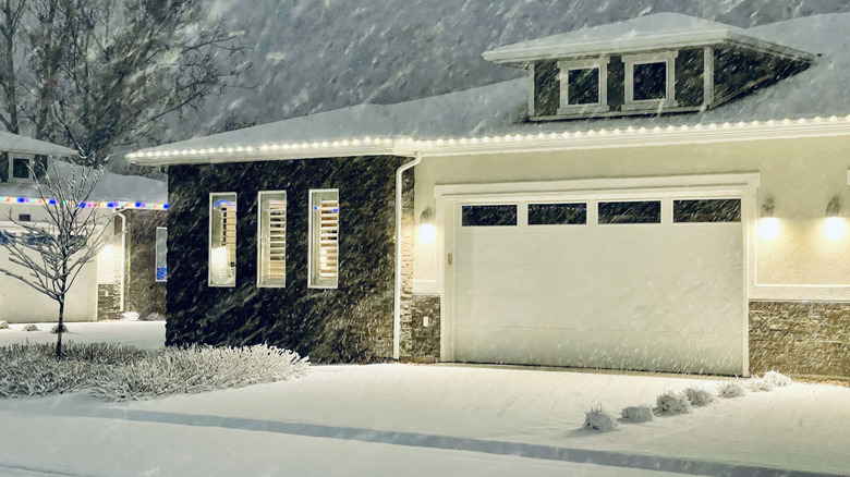 House with outdoor lights on during a snow storm