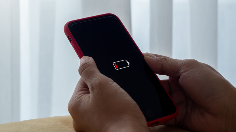 Person holding a smartphone with a low battery notification
