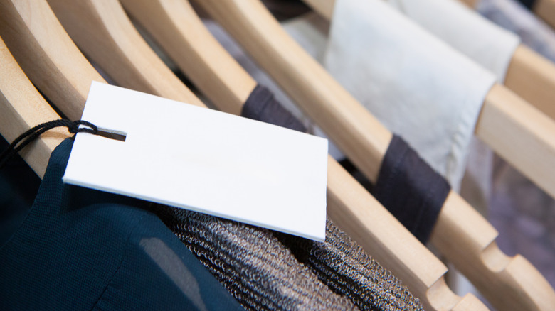New, unworn clothing still affixed with a tag hangs in a person's closet