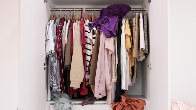 A messy closet on display for all to see, with clothes hanging haphazardly