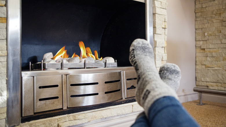 Person curled up next to gas fireplace