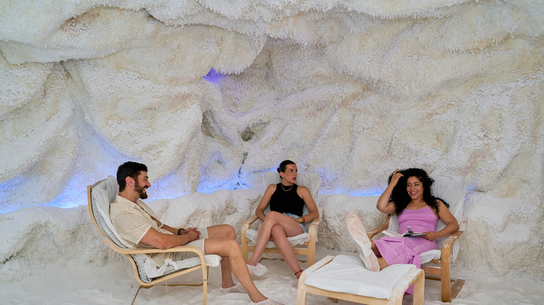 A group of three people sit on lounge chairs in a salt cave