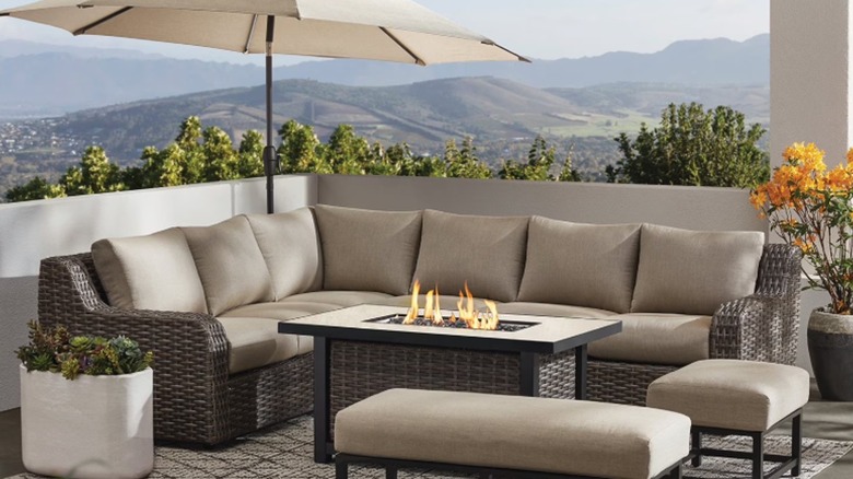 An outdoor sectional and fire pit set against a hilly background