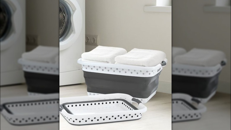 two laundry baskets, one open with towels and the other collapsed, beside dryer