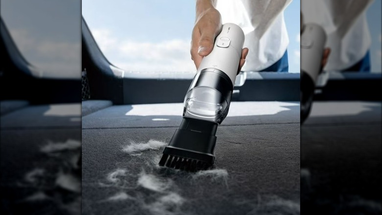 person using HOTO vacuum to clean pet hair from car