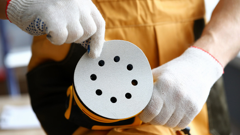 Close up of person in uniform changing the disc on an orbital sander