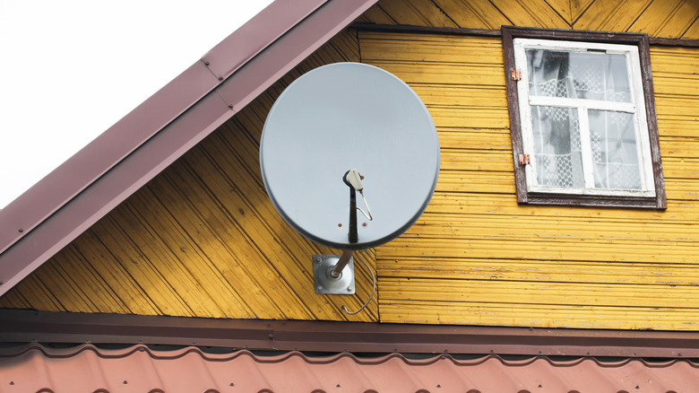 A satellite dish on a yellow home