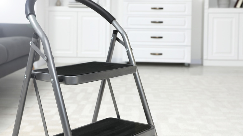 A folding metal step stool in a room with white and gray decor